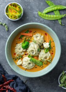 Top view of dumplings in a vibrant curry sauce with vegetables, perfect for traditional Asian cuisine lovers.